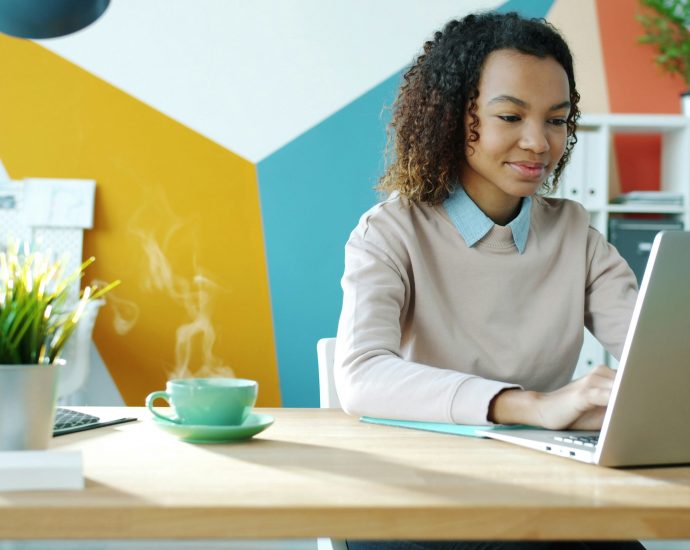 professionally dressed woman working on a laptop in a modern office