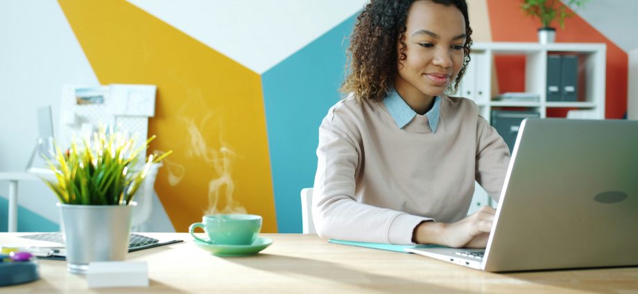 professionally dressed woman working on a laptop in a modern office